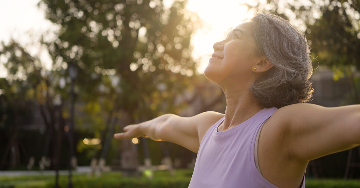 Woman with outstretched arms looking at the sun