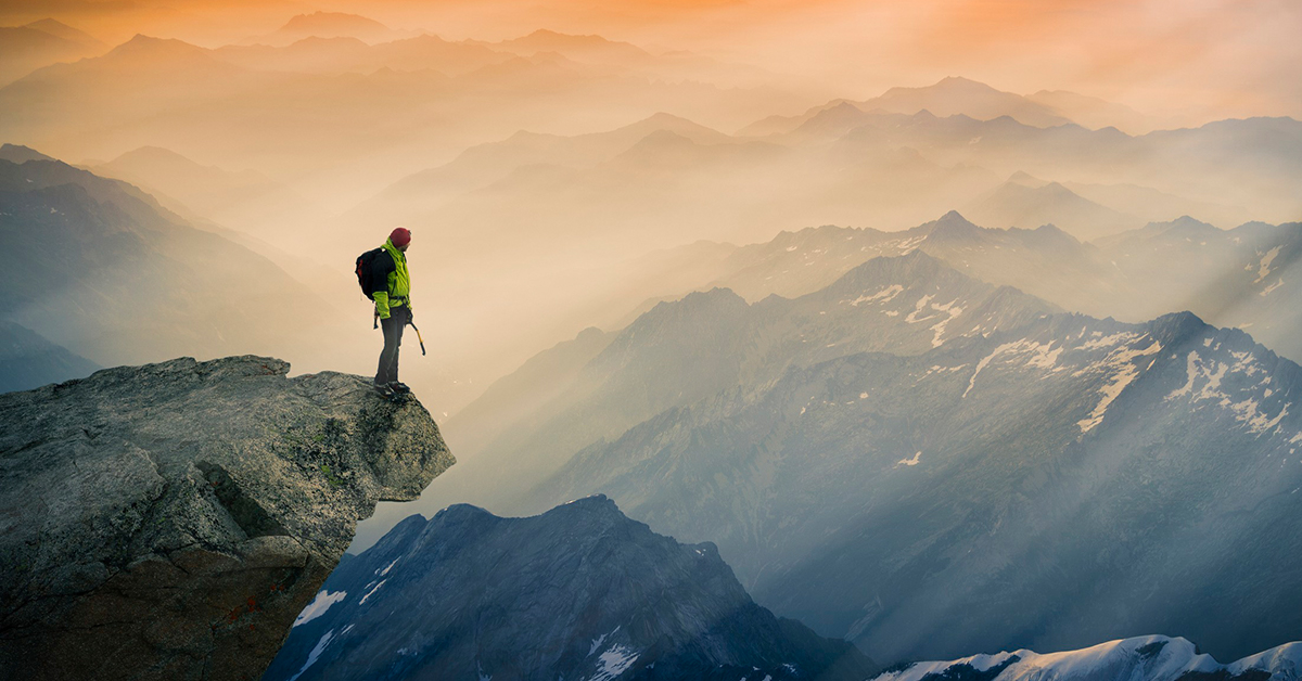Hiker on a mountain looking at the sun rise.