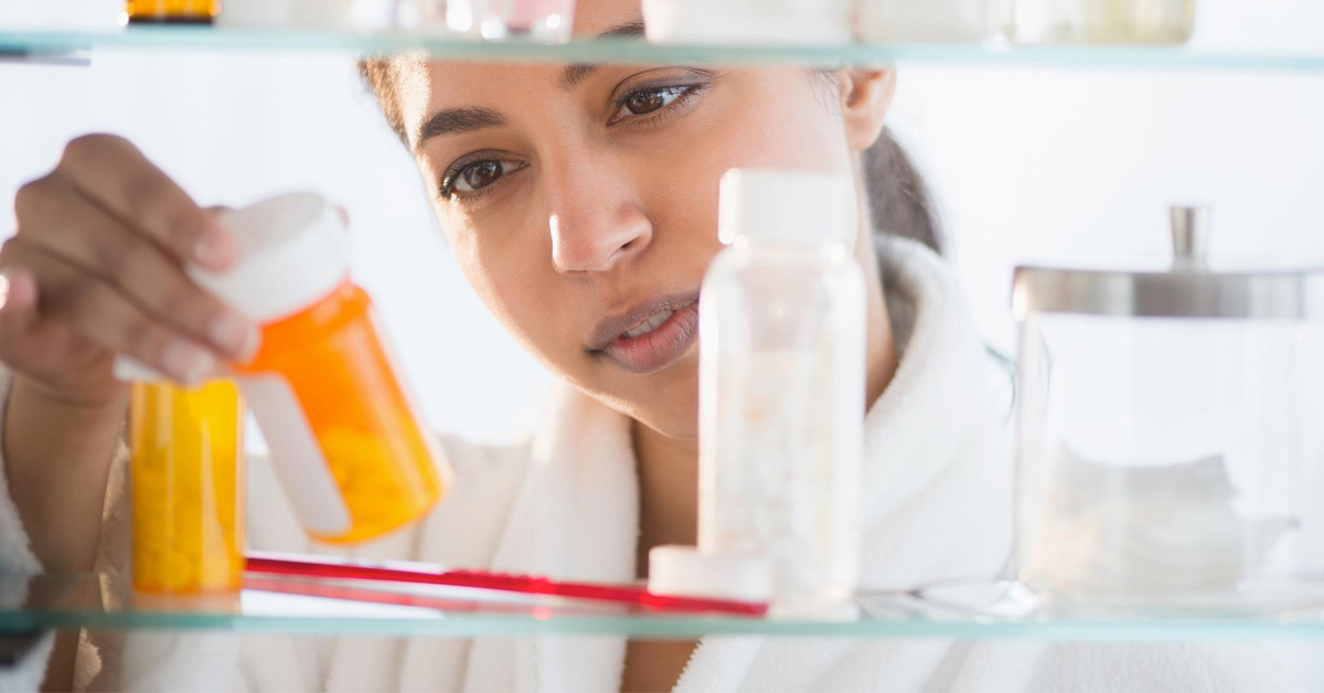 Woman sitting at home reading a prescription bottle