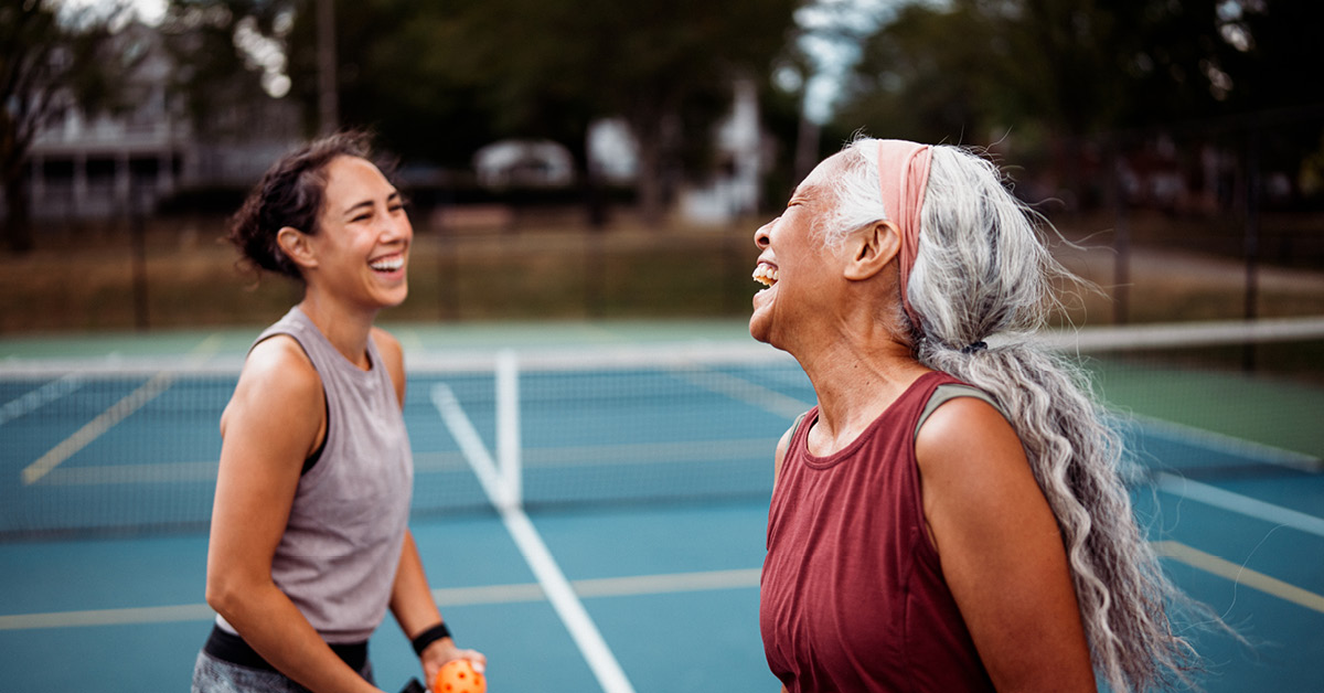 Two women on tennis court laughing