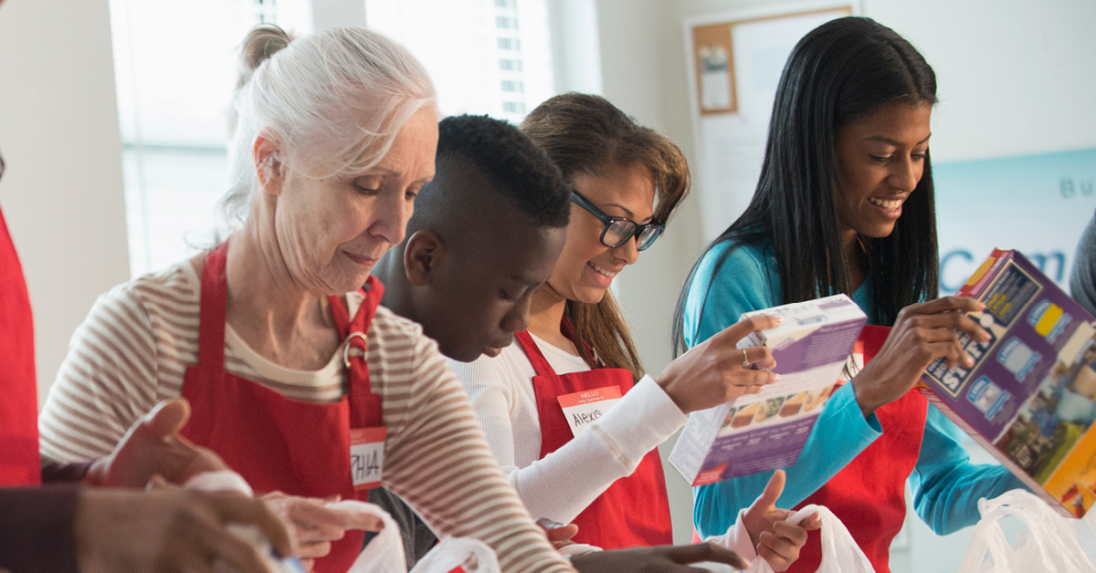 A group of volunteers putting boxes of food into bags