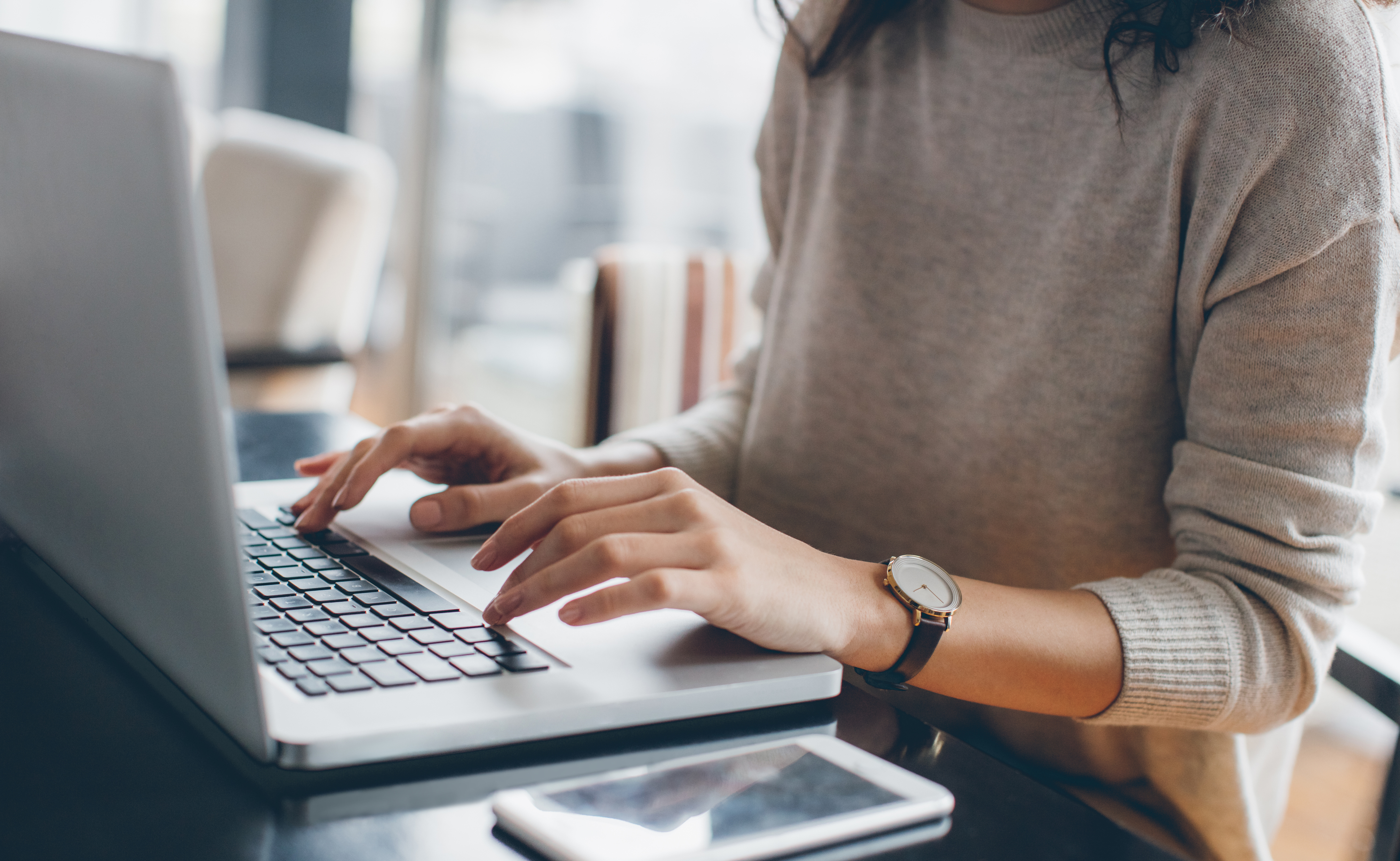 Person at desk typing on laptop.